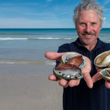 Pescatore con il so pescato e il mare alle spalle